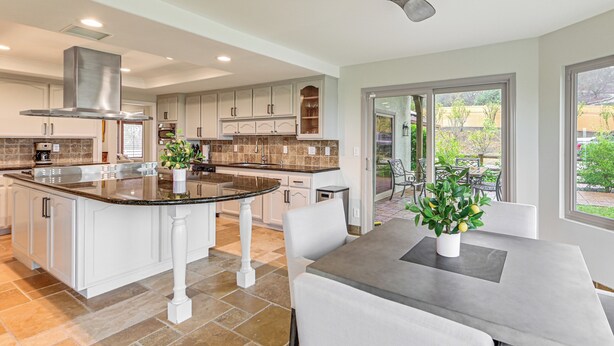 A modern kitchen with white cabinetry, a central island, and a dining area with a table and chairs. - Game Room, Hot Tub & Views! Luxe Temecula Estate (Temecula)