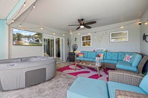 A covered patio with a hot tub, a teal sofa, and a ceiling fan. - Heated Pool & Boat Dock! Port Charlotte Getaway (Port Charlotte)