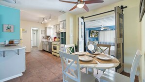 Una cucina con zona pranzo, ventilatore a soffitto e vista sul soggiorno.