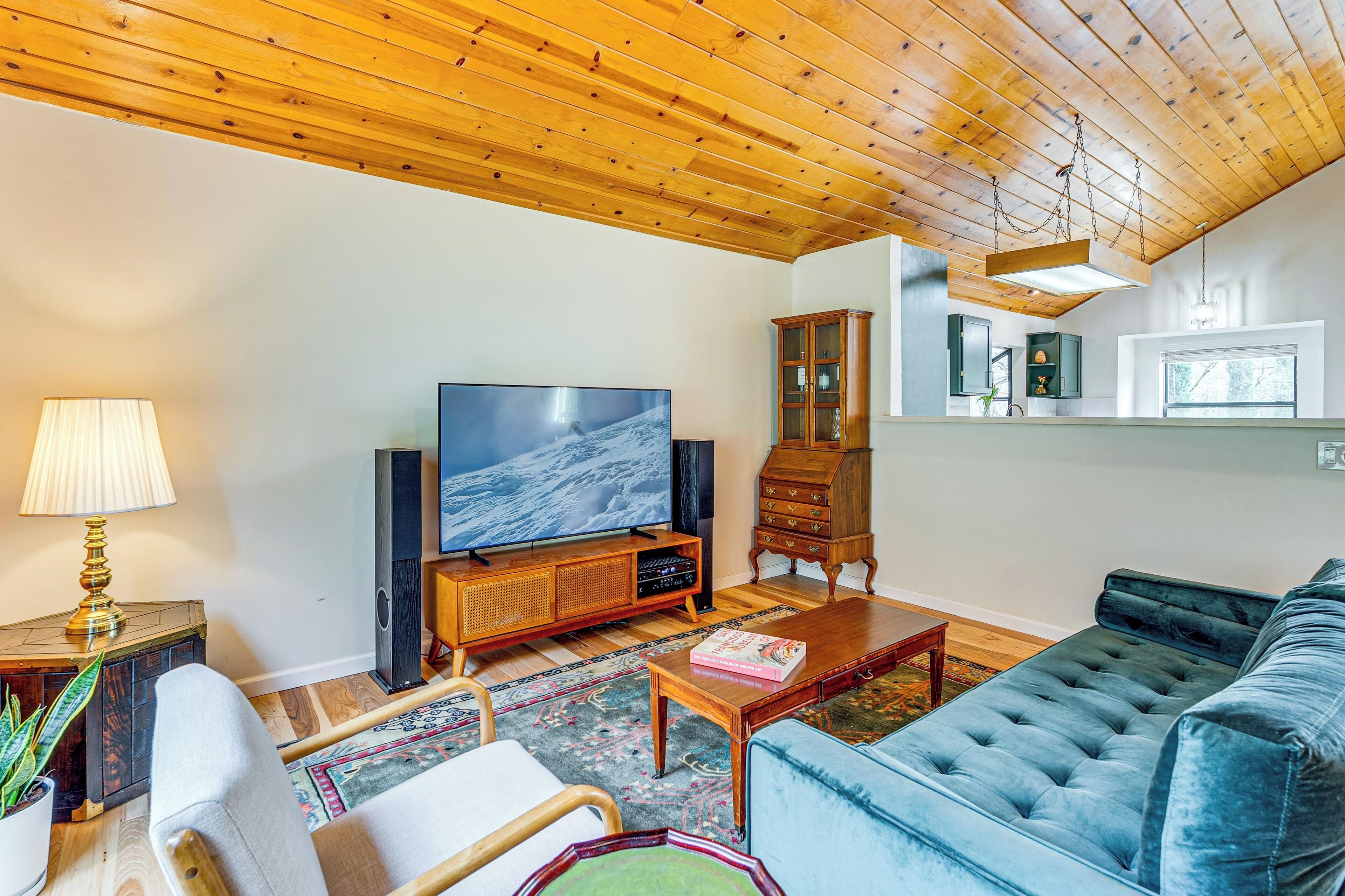 A living room with a television, wooden cabinet, and a blue sofa.
