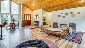 A spacious living area with a high wooden ceiling, a large bed, a dining table with chairs, and a fireplace. - Arts, History & Adventure! Gold Country Getaway (Grass Valley)