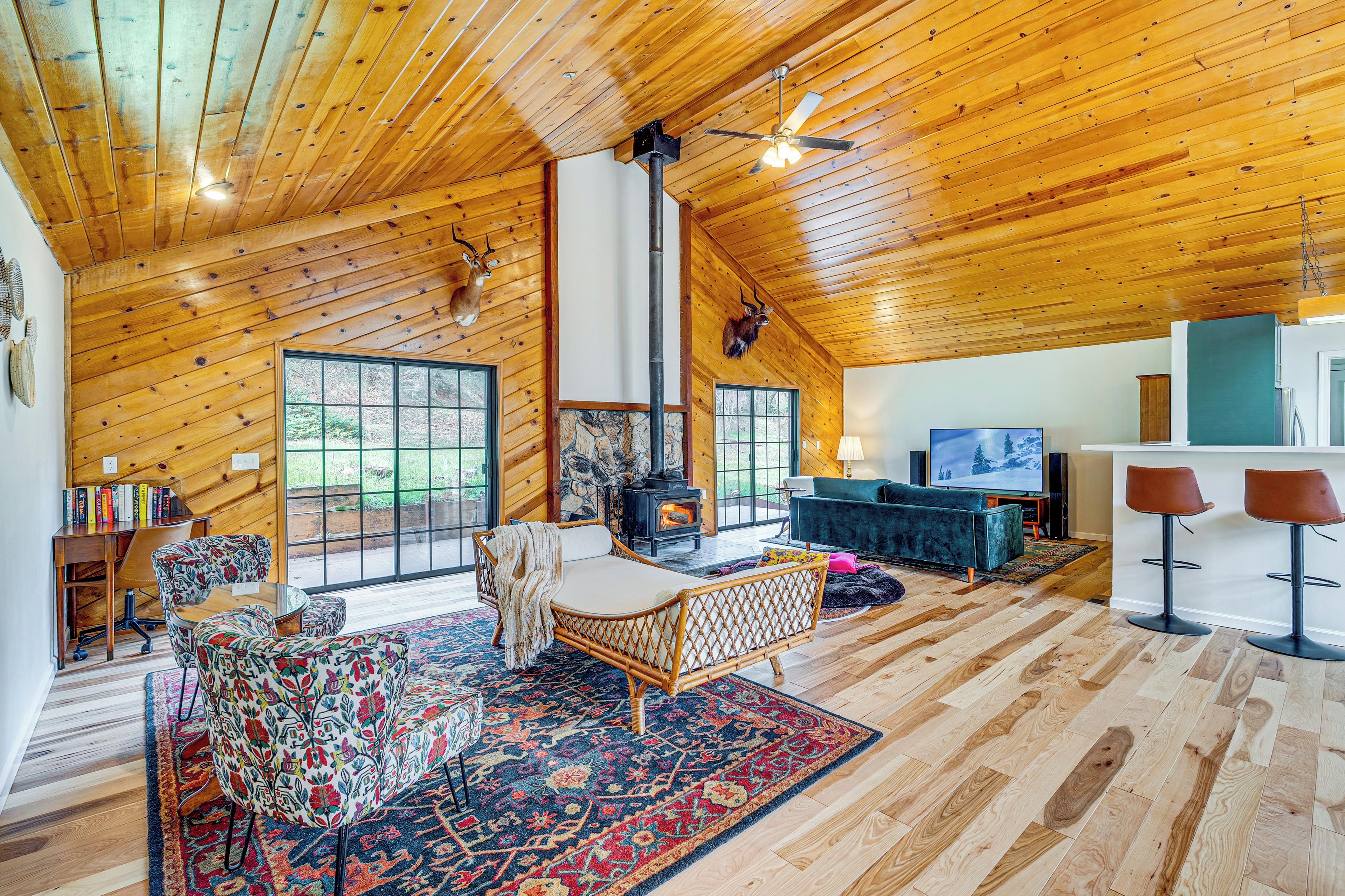 Interior acogedor de una cabaña con techo de madera, chimenea, sofá, una mesa de centro y televisor.