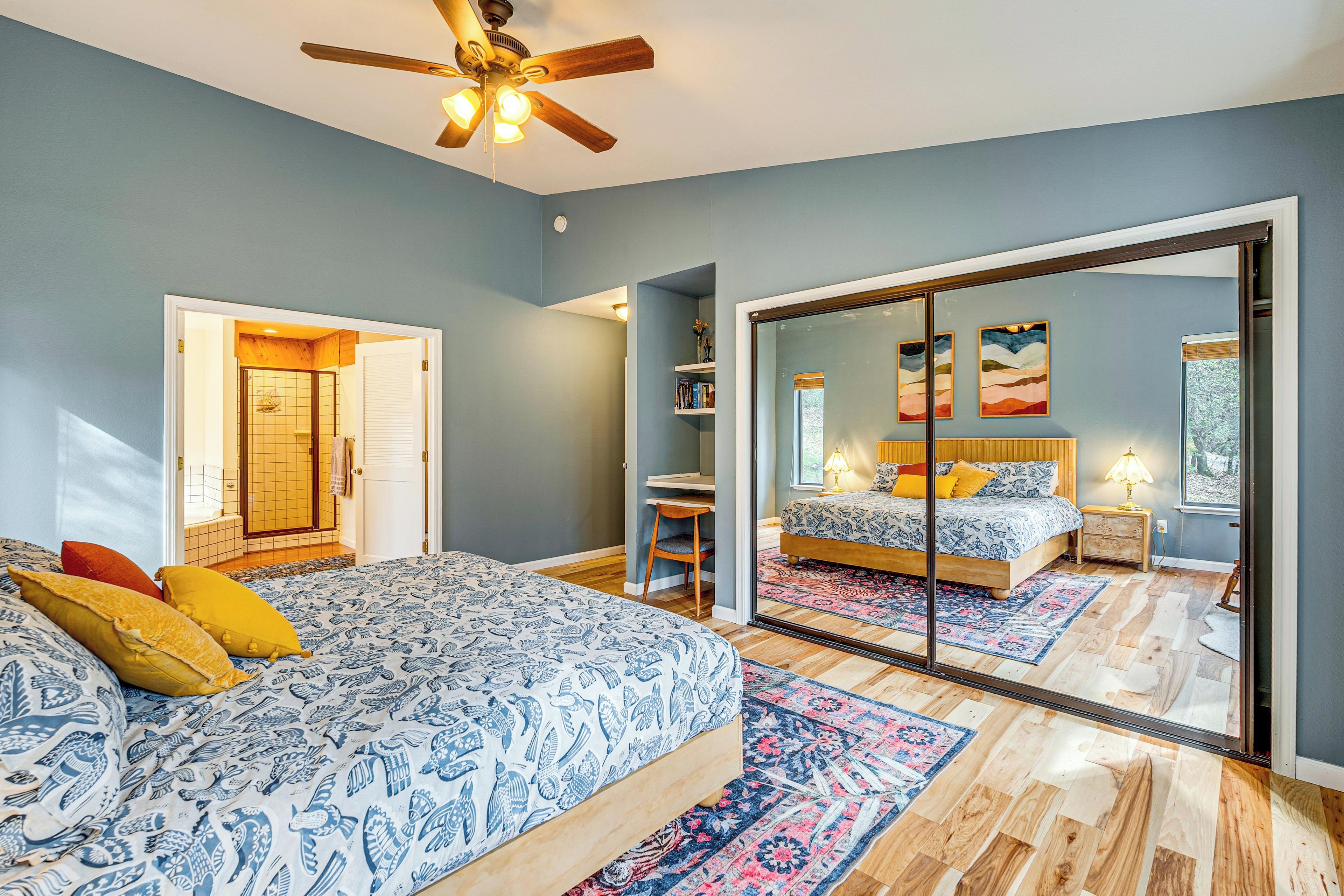 A bedroom with a large bed, a desk, and a sliding glass door leading to another room.