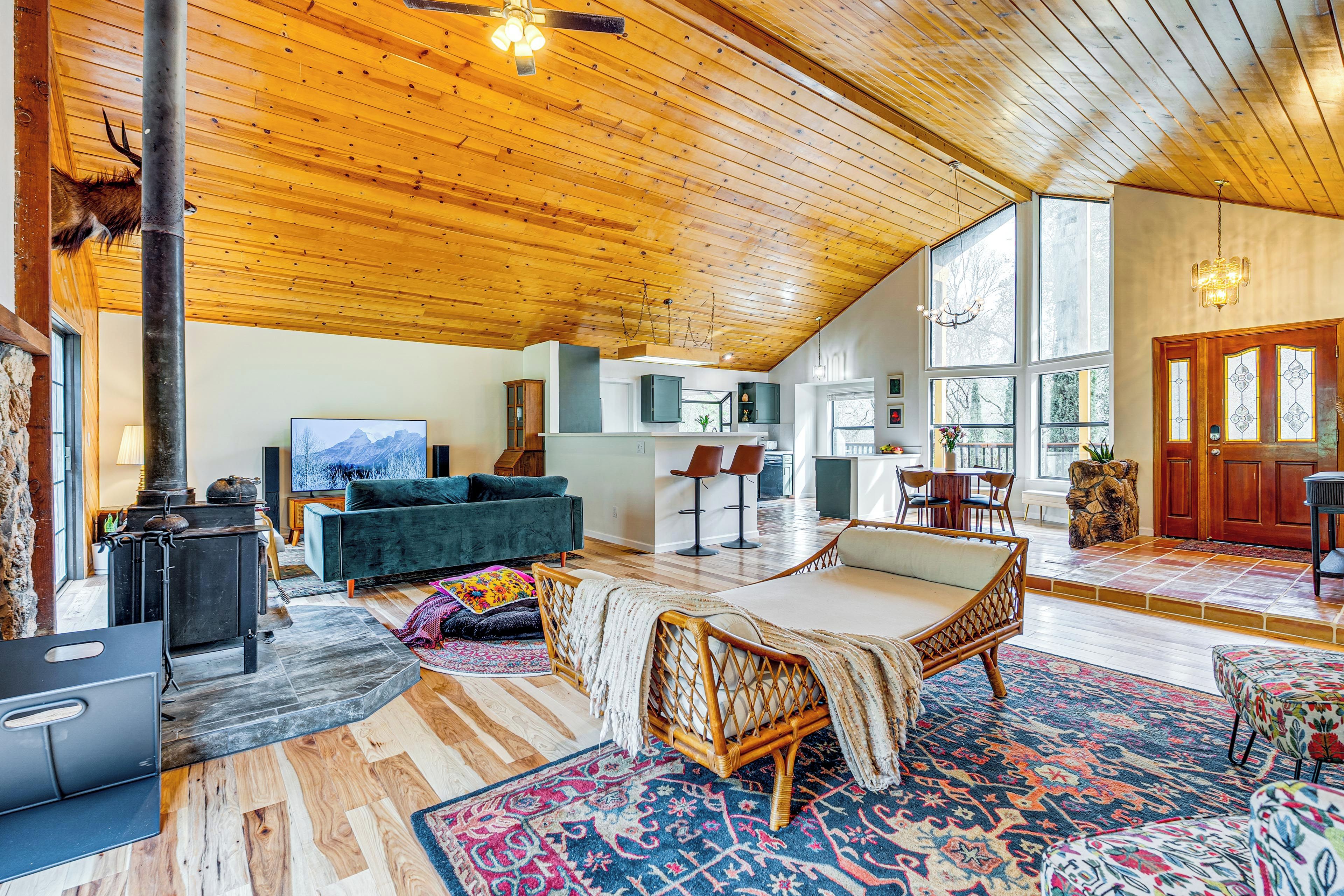 A spacious living area with a high wooden ceiling, a large window, and a cozy fireplace.