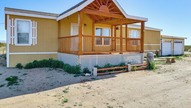 A single-story house with a wooden porch, a garage, and a fenced yard. - Hualapai Mountain Views & Deck! Yucca Getaway (Yucca)