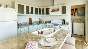 A kitchen with light blue cabinets, a white refrigerator, and a sink. - Hualapai Mountain Views & Deck! Yucca Getaway (Yucca)