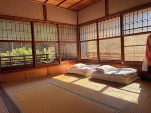 Une pièce de style japonais traditionnel, avec des tatamis, un lit bas en bois et des paravents en papier de riz (shoji).