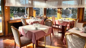 Ein Essbereich mit vier gedeckten Tischen, jeder Tisch mit Tischdecke und Tee-Service.