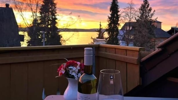 Ein Tisch mit einer Weinflasche und einem Glas vor einem Sonnenuntergang.