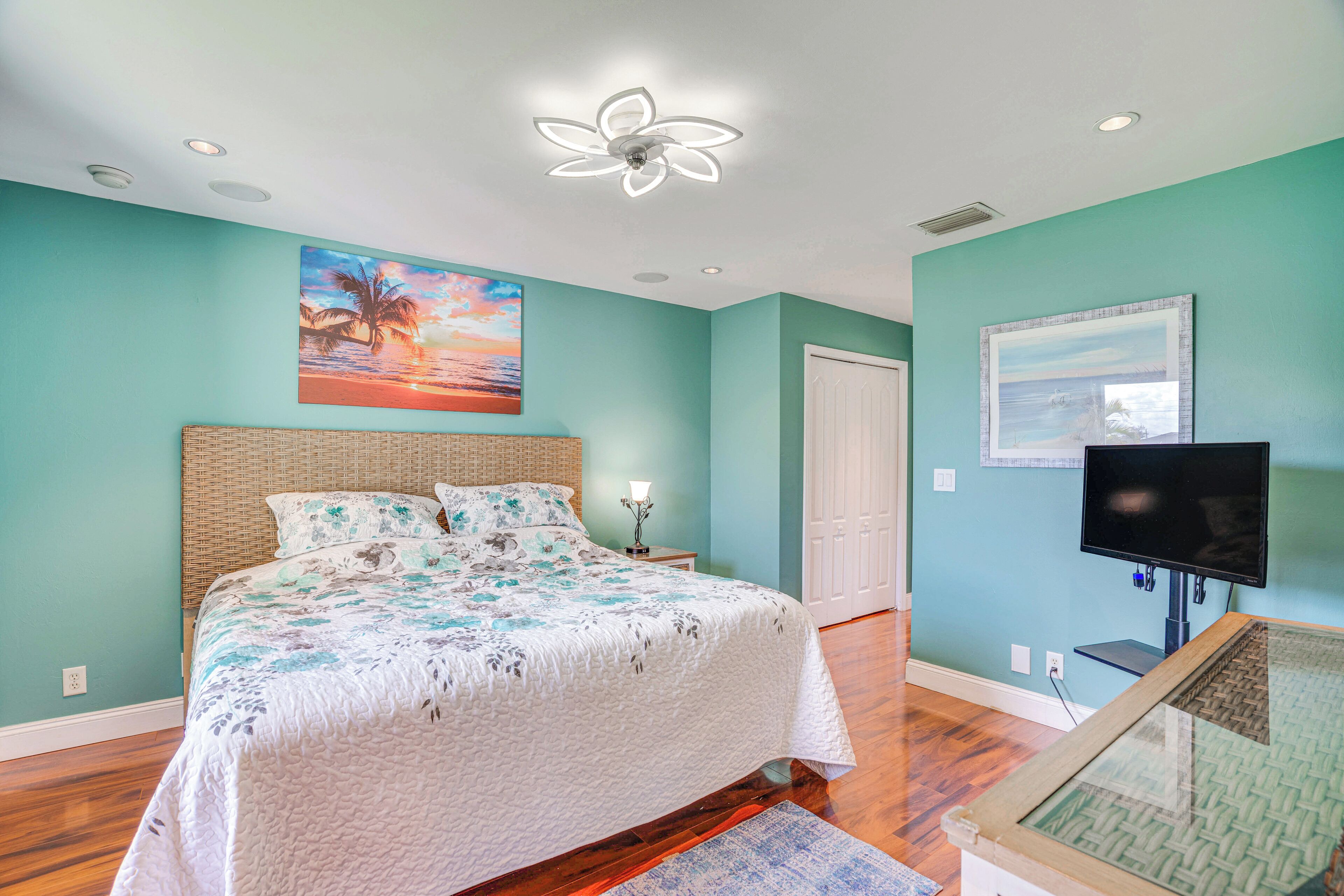 Un dormitorio con cama, televisor y obras de arte en las paredes.