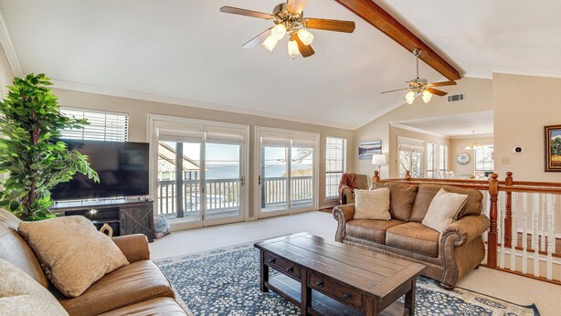 A spacious living room with a large television, leather sofas, a coffee table, and a ceiling fan. - 'texoma Shores Hideaway' Family Home w/ Water View (Pottsboro)