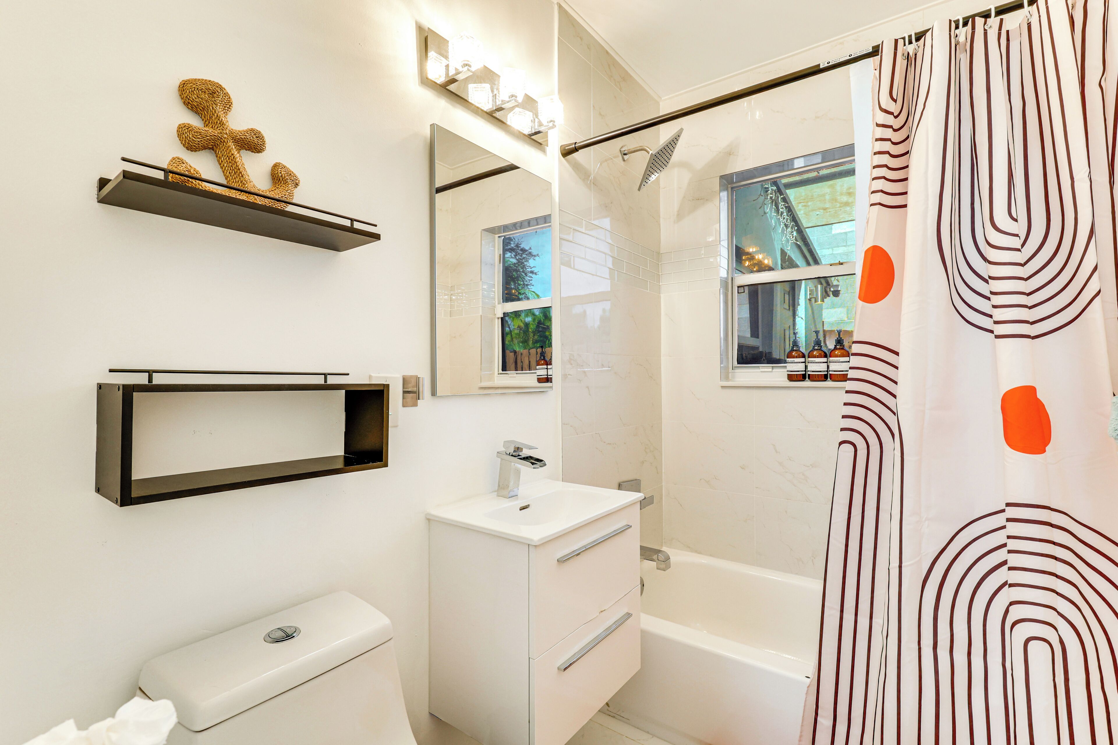 A modern bathroom with a toilet, sink, vanity, and bathtub.