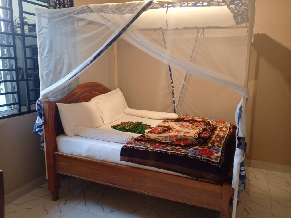 A bed with a canopy, a wooden headboard, and a floral bedspread.
