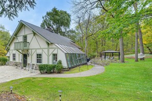 A traditional house with a large glass conservatory, surrounded by a well-maintained lawn and trees. - Tranquil Manor! Lake Geneva English Tudor Estate (Lake Geneva)