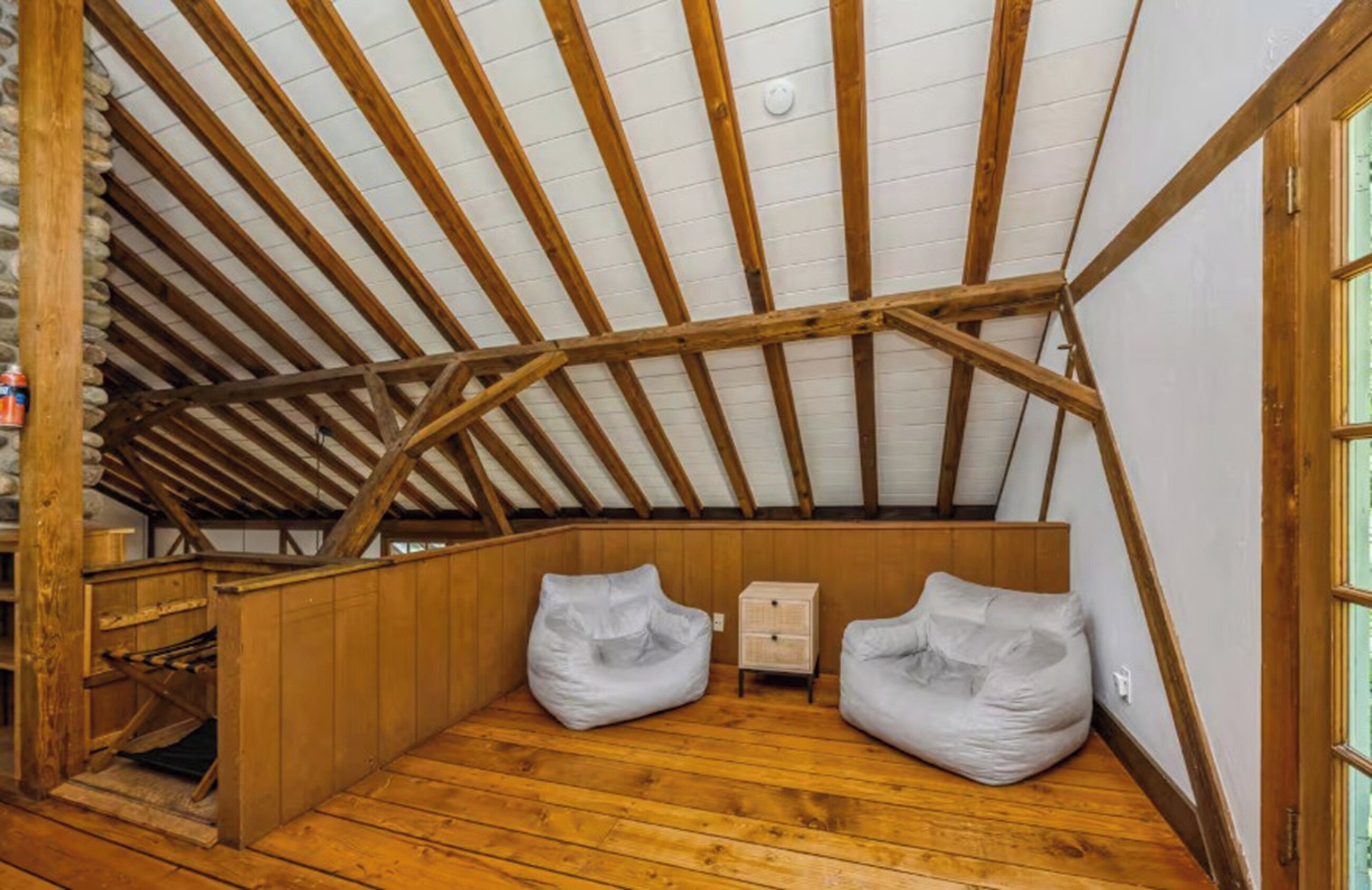 An attic room with wooden beams, a sloped ceiling, and two bean bags.