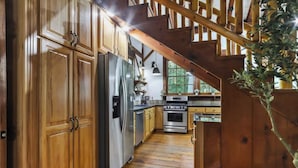 A wooden interior with a kitchen area, including cabinets, a refrigerator, an oven, and a staircase. - Tranquil Manor! Lake Geneva English Tudor Estate (Lake Geneva)