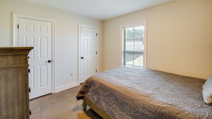 Une chambre à coucher avec un lit, une commode, deux portes et une fenêtre.