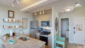 A modern kitchen with granite countertops, stainless steel appliances, and light wood cabinetry. - Villa 312 3 bedroom, 2 bathroom (Jekyll Island)