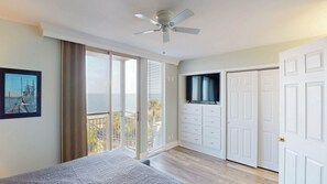 A bedroom with a balcony, a ceiling fan, a TV, and a wardrobe. - Villa 312 3 bedroom, 2 bathroom (Jekyll Island)