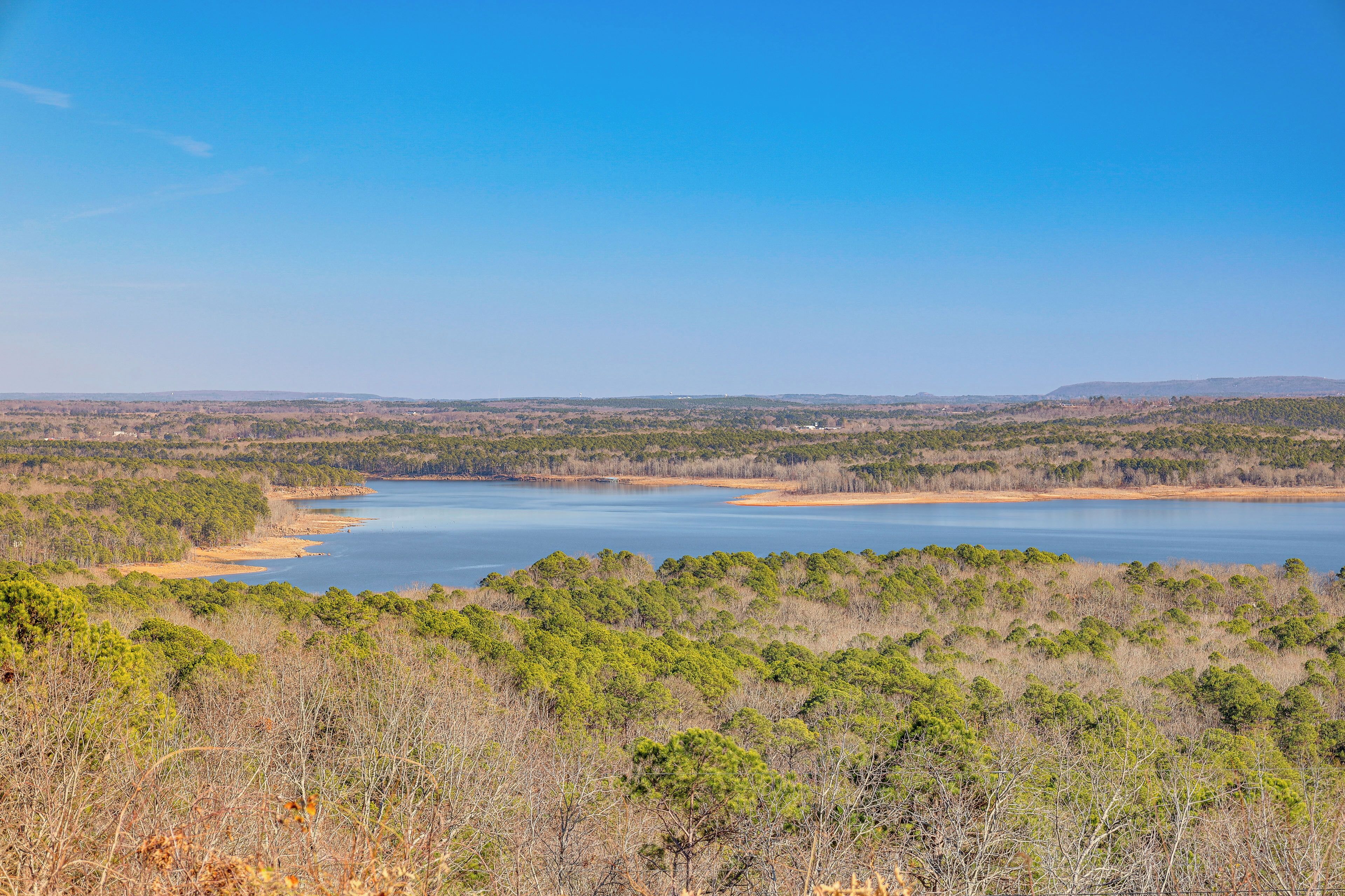 Une vue panoramique d’un lac entouré d’une forêt dense et de collines.