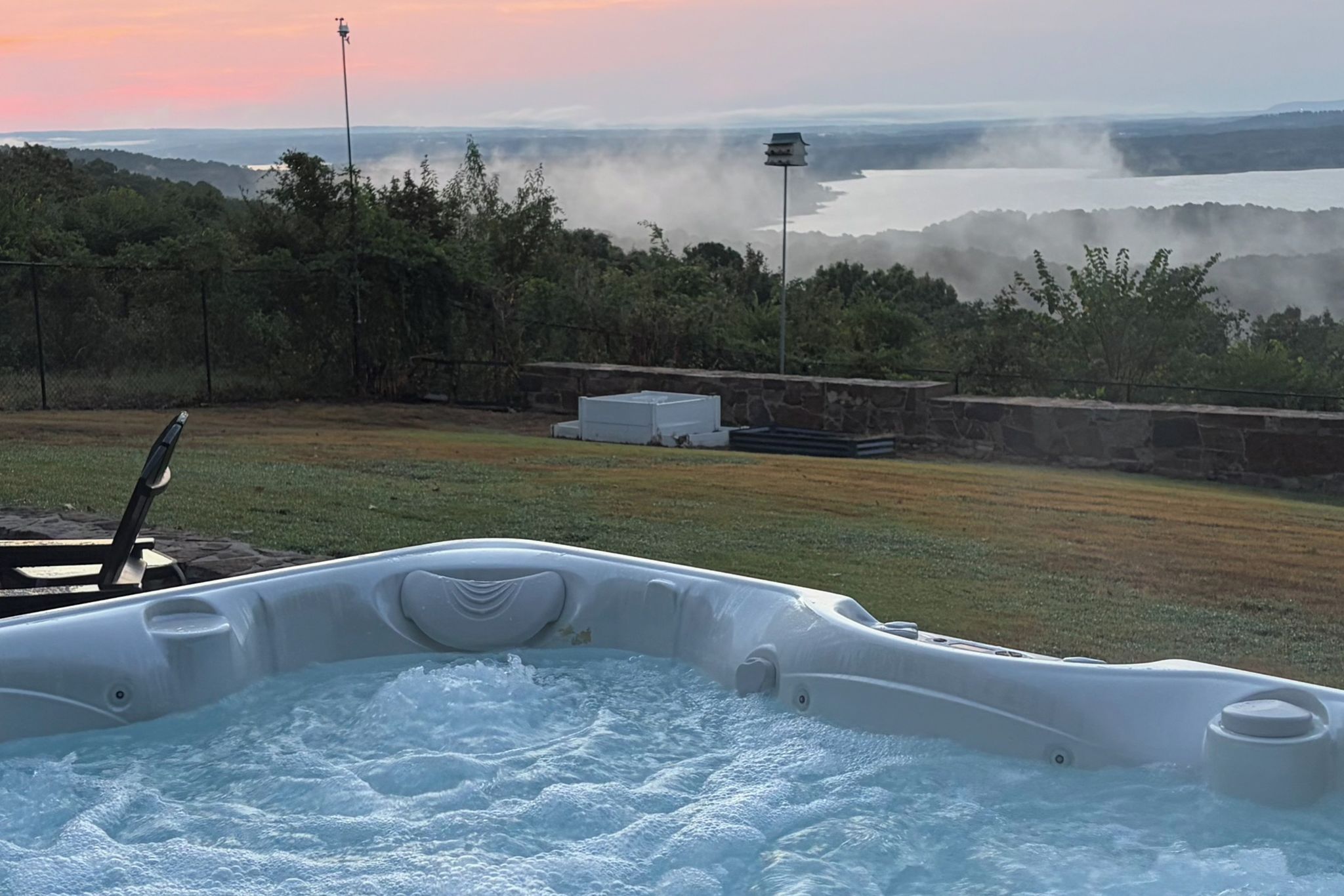Un jacuzzi con vista a un lago y colinas boscosas al fondo.