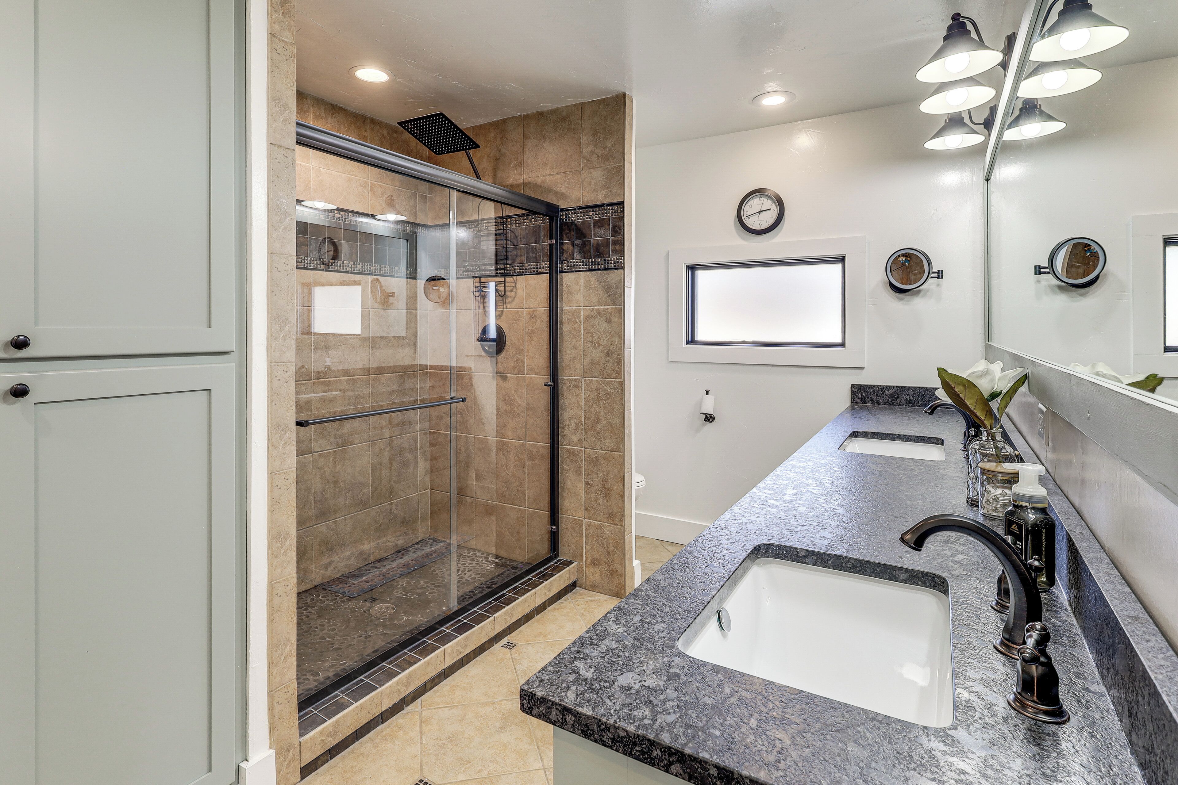 A modern bathroom with a glass-enclosed shower, two sinks, and a large mirror.