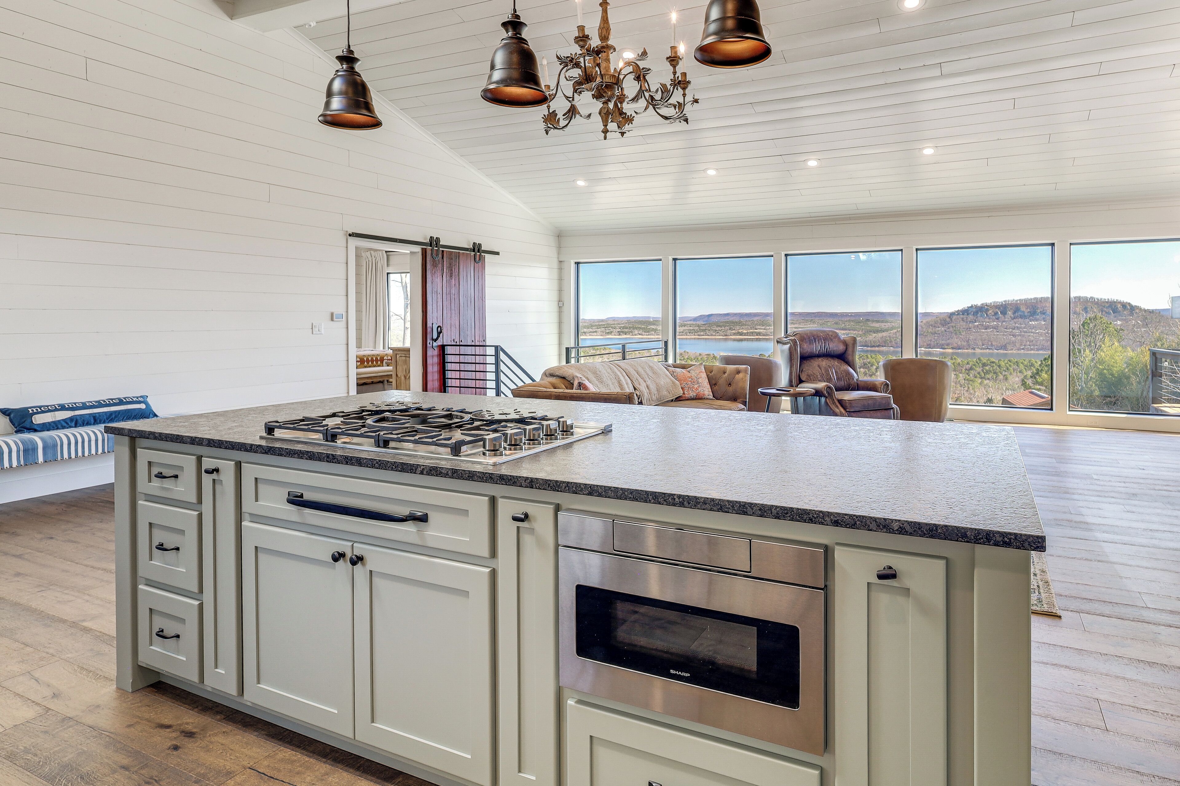 Cozinha ampla com uma ilha grande, eletrodomésticos de aço inoxidável e vista para o exterior.