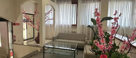 A living room with a sofa, a glass coffee table, and a red rug.