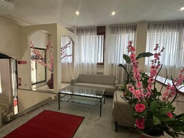 Una sala de estar con un sofá, una mesa de centro de vidrio y una alfombra roja.