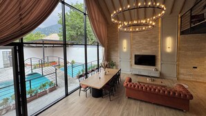 Uma sala de estar moderna com uma janela grande, piscina, lareira e área de refeições.