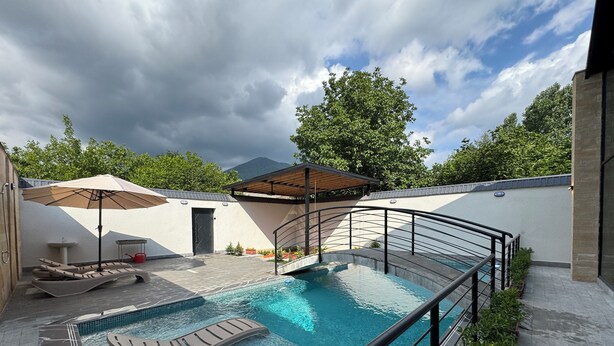 Uma piscina com espreguiçadeiras e um pérgola.