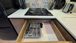 Cozinha com fogão, gaveta de utensílios e painel de azulejos.