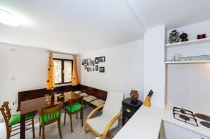 A compact kitchen with a dining area, a stove, and a window with curtains.