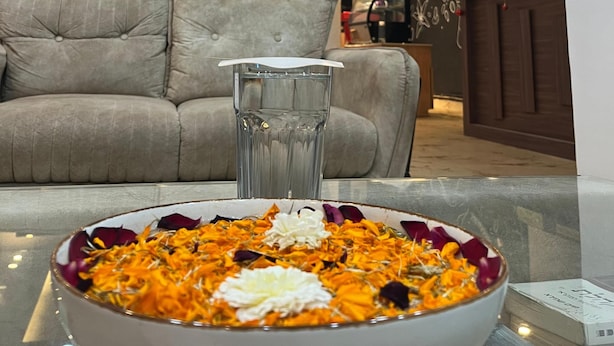 Un salon moderne avec un canapé, une table en verre et un vase décoratif rempli de fleurs.