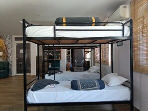 En køjeseng med to niveauer, et skrivebord og en stol i baggrunden.