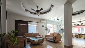Un vaste salon doté d’un haut plafond, d’un ventilateur de plafond et d’une cloison en verre. On y trouve deux canapés et une table basse.
