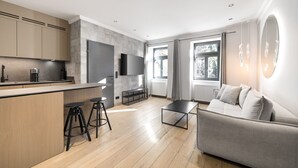 Een moderne keuken met een inbouwfornuis, barstoelen en een grote televisie.
