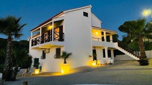 Una casa moderna de dos pisos con un balcón y un área de piscina, con una escalera que lleva al piso superior.