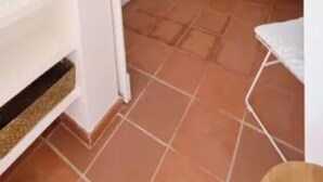 Una habitación pequeña y blanca con una cama, una mesa y un ventanal.