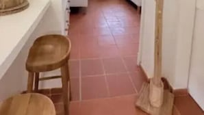 Un pasillo estrecho con un banco de madera, un taburete pequeño y una estructura de madera a la derecha.