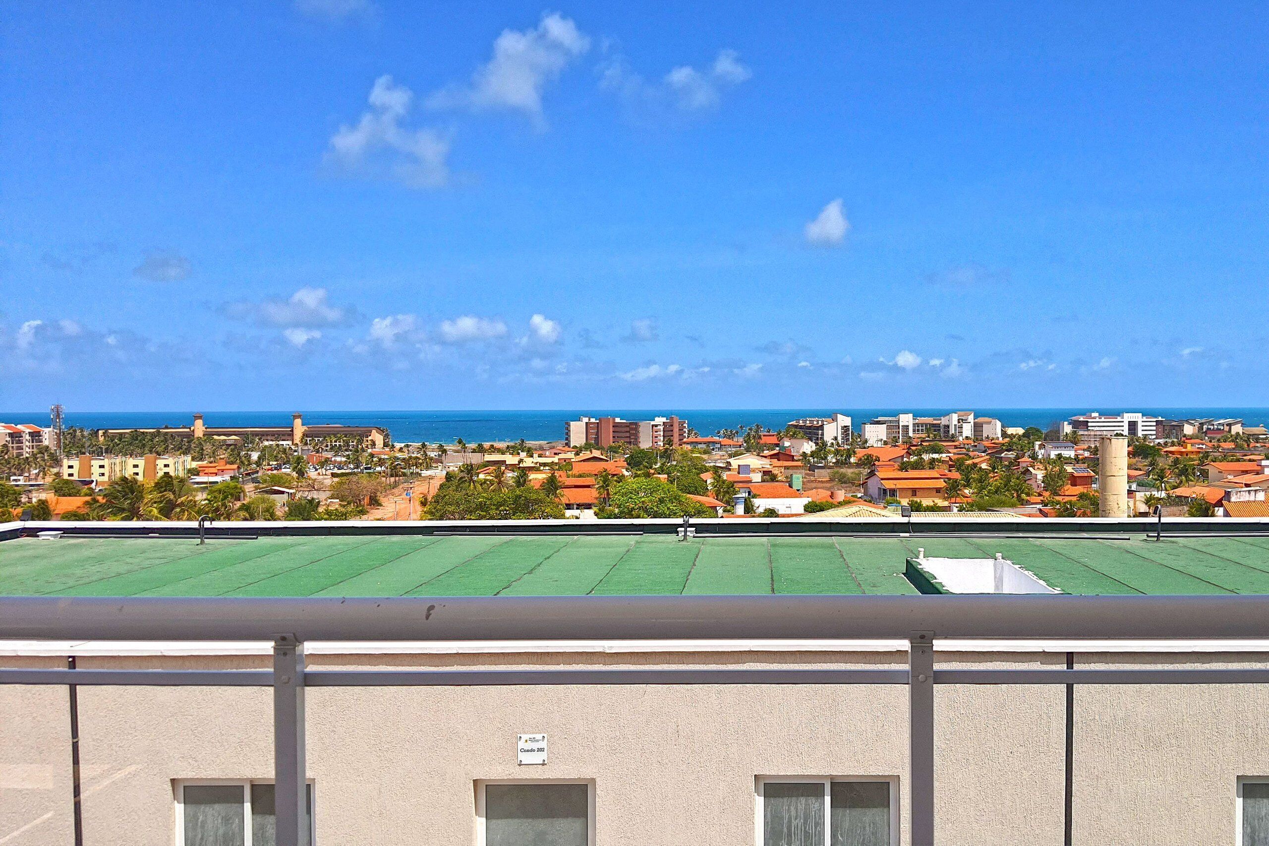 A view from a balcony overlooking a coastal cityscape with a clear sky.