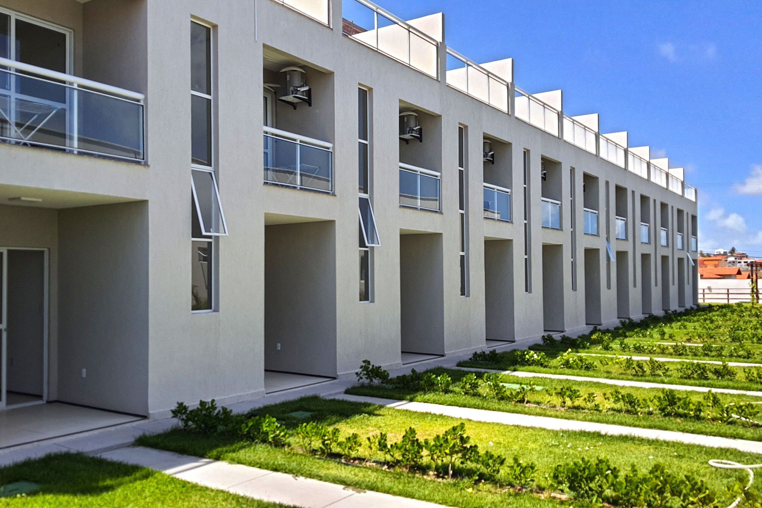 A modern building with a linear facade, multiple balconies, and a well-maintained garden area.