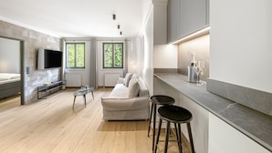 Un salon moderne avec un canapé, un téléviseur et un coin bar équipé de tabourets.