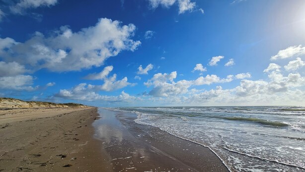 A beach with sand, waves, and a clear sky. - Charming 3BR/2BA - 1/2 Block to Beach - Sleeps 8 from Rent On Padre (South Padre Island)