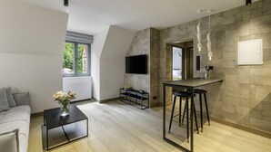 Una sala moderna con un sofá, una mesa de centro y un televisor montado en la pared.