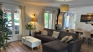 A modern living room with a sectional sofa, a white coffee table, and a dining area with a table and chairs. - Ideal for vacations with family or friends: semi-detached house 150 m². (Mougins)