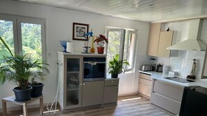 A modern kitchen with a dishwasher, a microwave, and a sink. There are potted plants and a framed artwork on the wall. - Ideal for vacations with family or friends: semi-detached house 150 m². (Mougins)