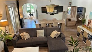 A modern living room with a sectional sofa, a dining area, and a kitchen. - Ideal for vacations with family or friends: semi-detached house 150 m². (Mougins)