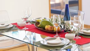 Una mesa de comedor dispuesta con platos, cubiertos, copas y una botella de vino.