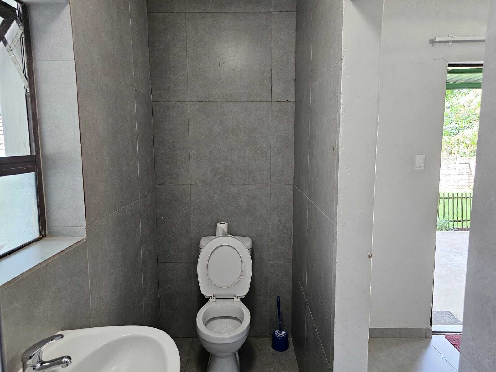 A bathroom with a toilet, a sink, and a window.
